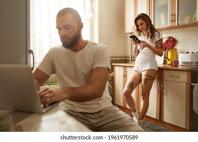 Man working at laptop at table while his lovely girlfriend using her smartphone