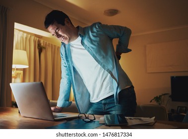 Man Working Late At Night Suffering From Back Pain