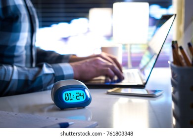 Man working late. Workaholic or being behind schedule concept. Business person in modern office building or home at night using laptop. Time in digital clock on table in workstation.  - Shutterstock ID 761803348