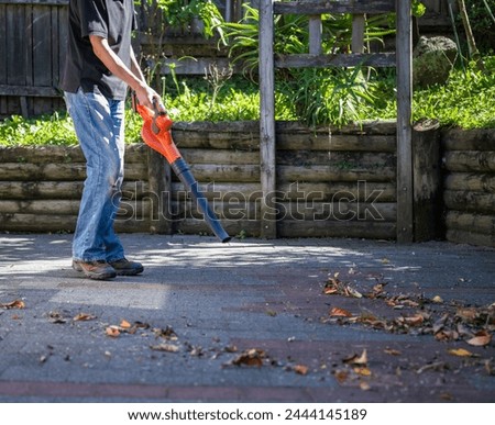 Man working with a leaf blower in the backyard. 