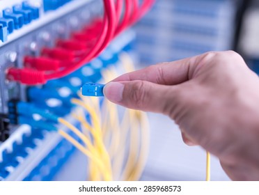 man working in network server room with fiber optic hub for digital communications and internet - Powered by Shutterstock - Get 15% off with code: PIKWIZARD15