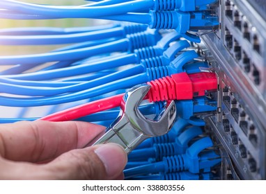man working in network server room with wrench