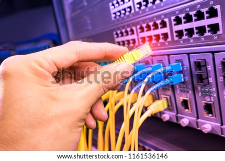 man working in network server room with fiber optic hub for digital communications and internet