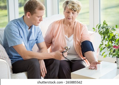 Man Working As A Nurse Taking Blood Pressure