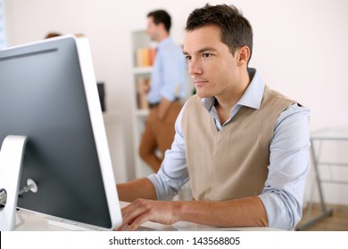 Man Working In Office In Front Of Desktop Computer