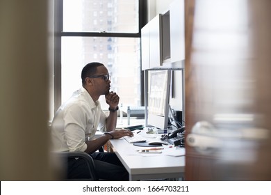 A man working in an office seated at a desk. Looking at a computer screen. - Shutterstock ID 1664703211