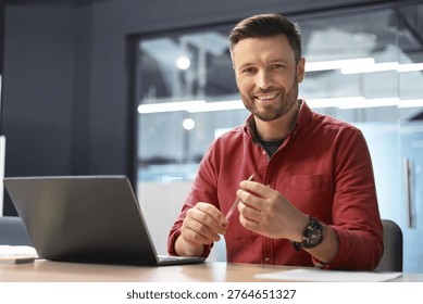Man Working in Office Setting Using Laptop and Smiling During the Day