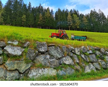 Man Working on the Austrian Mountains with Tractor and trolley in the Fields Nature landscape of Austria 
