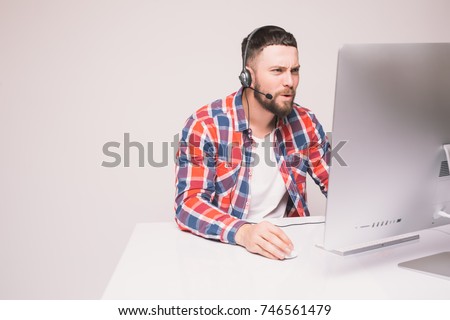 Man working on computer with headset in office