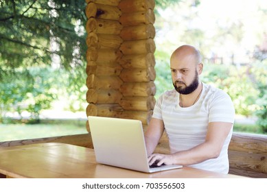  Man working on computer outdoor. Productive time outside the office. Handsome businessman with beard working on summer terrace. - Shutterstock ID 703556503