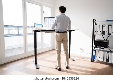 Man Working On Computer At Standing Desk In Home Office 