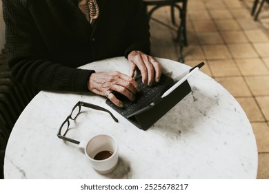 Man working on digital tablet at coffee shop, black glasse on white table. no face. - Powered by Shutterstock