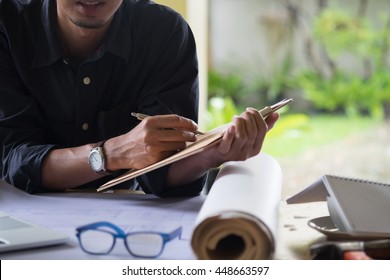 Man Working On His Plane Project At Site Construction Work. Holding A Cup Of Coffee And Pen For Check List.