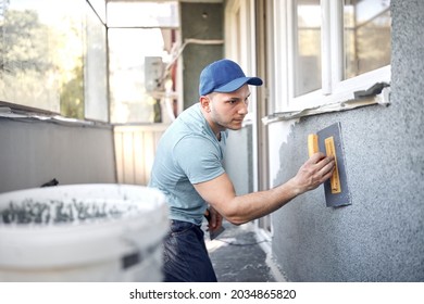 Man working on a house facade. - Shutterstock ID 2034865820