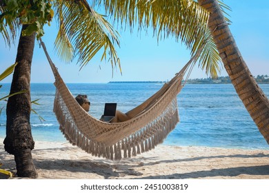 man working on laptop computer while relaxing in beach hammock, freelance worker, remote job via internet - Powered by Shutterstock