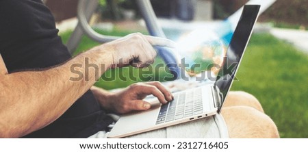 Man working on laptop in garden. Close-up of male hands typing
