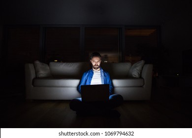 A man working on a laptop at home at night.