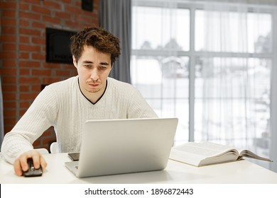 A Man Working On A Laptop At Home At Bright Kitchen