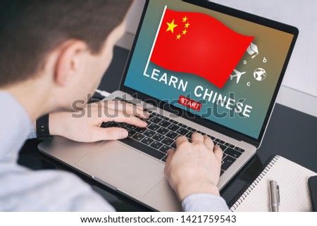 Man working on laptop with LEARN CHINESE on a screen. Education learning Chinese language school concept
