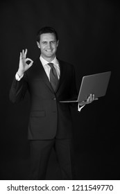 Man Working On Laptop And Making Ok Gesture On Black Background. Happy Businessman Or Manager Smiling In Blue Formal Suit. Technology For Business. Fashion And Dress Code. Blogging And Weblog