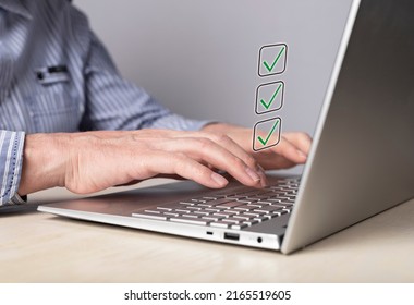 Man Working On Laptop And Marking Achieved Goals With Ticks Or Taking Survey And Noting Right Answers. Checklist, Planning, Time Management Concept. Male Hands At Computer Keyboard. High Quality Photo