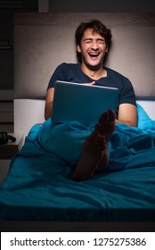 Man Working On Laptop At Night In Bed