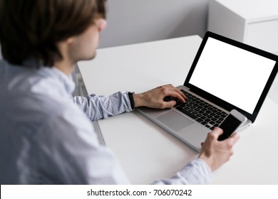 A man working on a laptop and a smartphone. Laptop with blank screen. A young freelancer. - Shutterstock ID 706070242