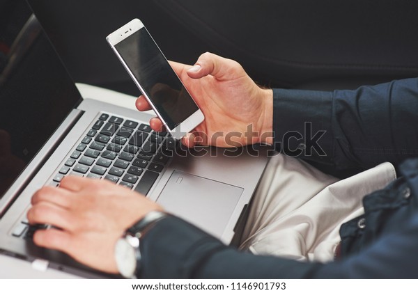 Man is a man working on a laptop and testing on\
mobile devices