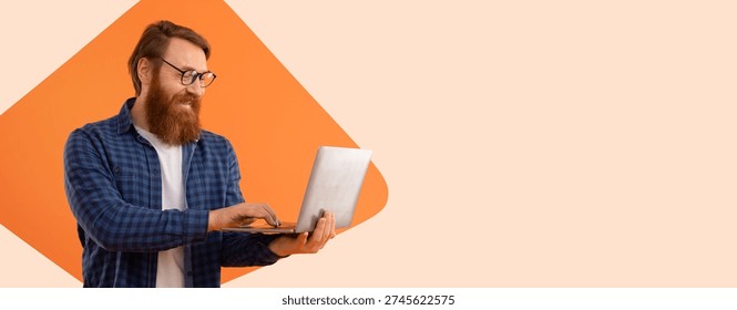 Man Working on Laptop While Standing in Front of an Orange Background in a Simple Setting