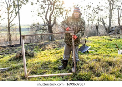 Man Working On Vegetable Winter Garden For Raised Bed Cold Frame In Ukraine Dacha Standing Holding Equipment Hammer