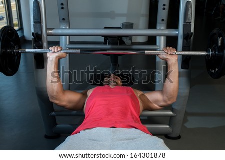 Man Working Out in the Gym. Young Men In Gym Exercising On The BenchPress