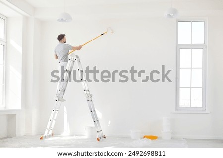 Man working as a painter, using a roller brush to paint a wall during a home renovation. This construction highlights the detailed and essential work involved in home improvement projects.