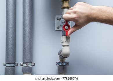Man working at pipes. Turning on or turning off water supply in the boiler room. Plumbing concept.