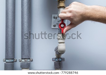 Man working at pipes. Turning on or turning off water supply in the boiler room. Plumbing concept.