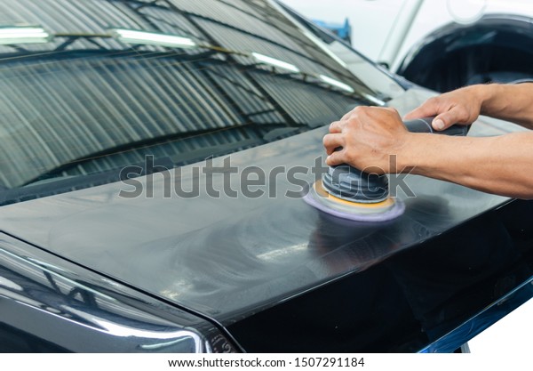 Man\
working for polishing, coating cars. polishing of the car will help\
eliminate contaminants on the surface of the car.Waxing the car\
surface will cause shine after polishing the\
car.