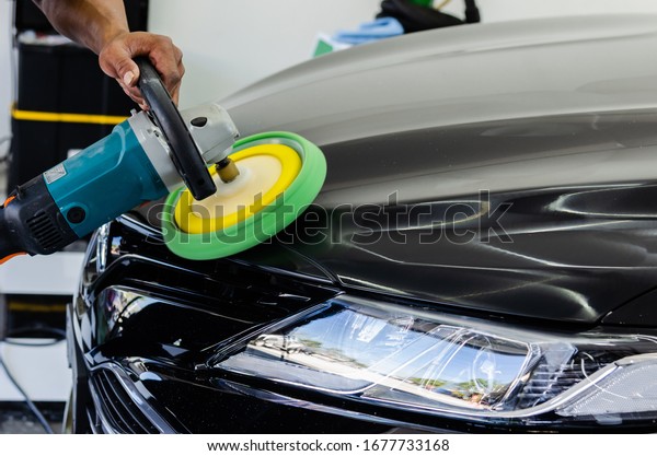 Man\
working for polishing, coating cars. polishing of the car will help\
eliminate contaminants on the surface of the car.Waxing the car\
surface will cause shine after polishing the\
car.