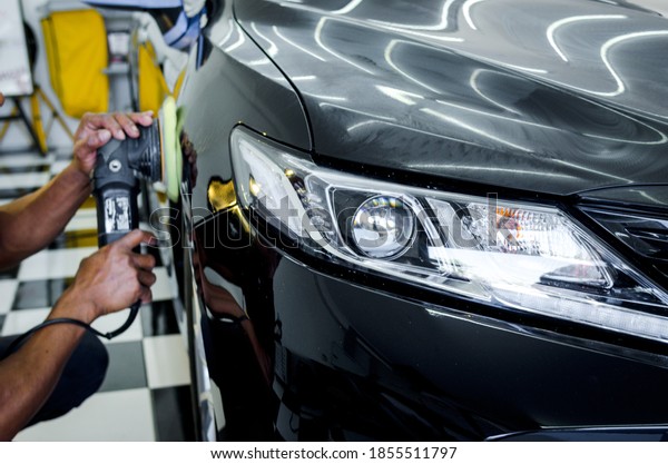 Man working for polishing, coating cars.\
polishing of the car will help eliminate contaminants on the\
surface of the car.Focus on car\
headlights
