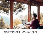 Man working remotely with laptop overlooking a scenic mountain view