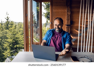 Man working remotely on laptop from mountain cabin - Powered by Shutterstock