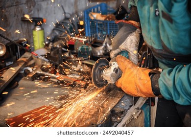 Man working with rotary angle grinder at workshop, closeup detail, orange sparks flying around - Powered by Shutterstock