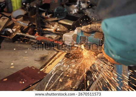 Man working with rotary angle grinder at workshop, closeup detail, orange sparks flying around