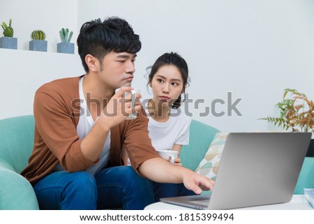 Man working seriously at home and woman looking at him. Woman wishes man accompany her more. Concept of 