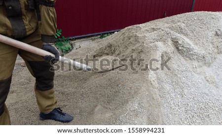 A man working with a shovel at a construction site loads sand
