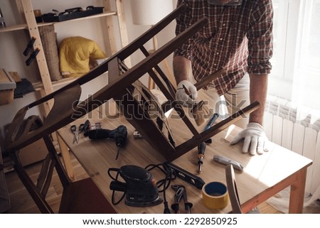 Man working in a small home workshop for furniture repairing and restoration.