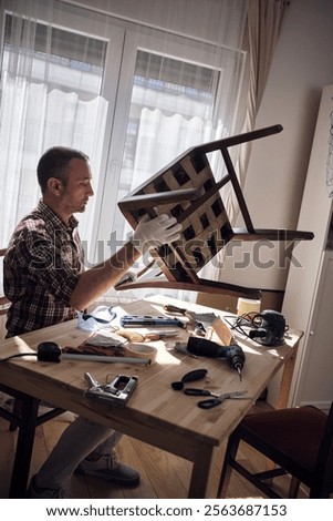 Man working in a small home workshop for furniture repairing and restoration.