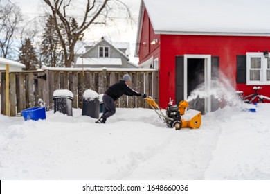 Man working with a snow blowing machine. A man removes snow by using a snow throwing machine. Intentional motion blur