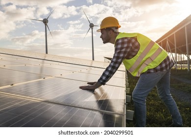Man working for solar panels and wind turbines - Renewable energy concept - Soft focus on male worker hands