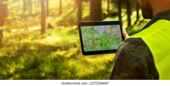 man working with topographic map data on digital tablet in forest. banner with copy space - Powered by Shutterstock