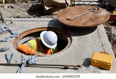 Man working underground through a manhole in the street