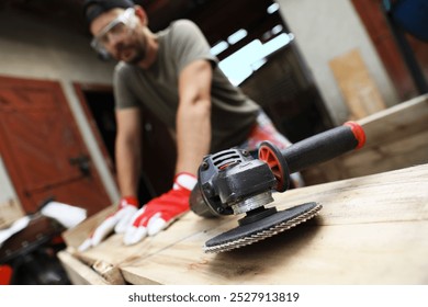 Man working with wood outdoors, focus on angle grinder - Powered by Shutterstock